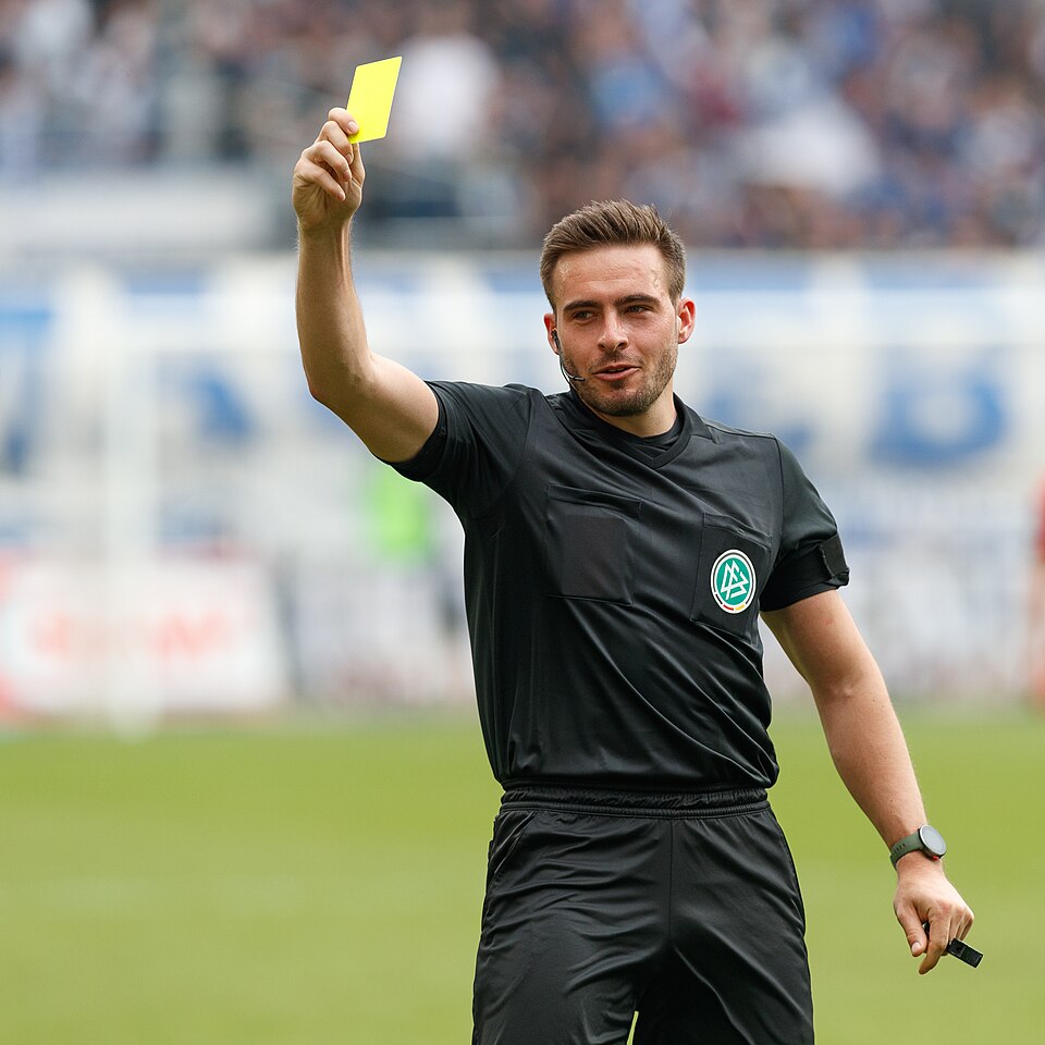 Árbitro mostrando tarjeta amarilla en un partido de liga argentina